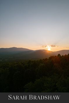 the sun is setting over some trees and hills