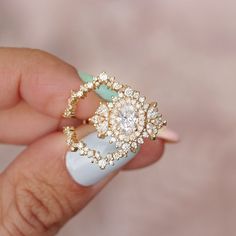 a woman's hand holding an engagement ring with diamonds on the top and bottom