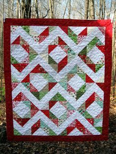 a red and green quilt hanging in the woods