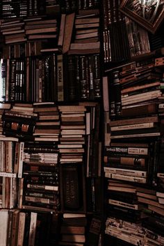 a large amount of books are stacked on top of each other in the dark room