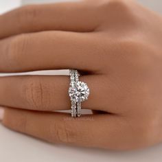 a woman's hand with a diamond ring on top of her finger and the other hand holding an engagement ring