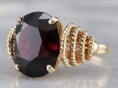 What an amazing ring to add to your collection! This fiery, glittering garnet is rich red in color and boasts a beautiful internal sparkle! Its oval cut shape is flattering on any finger, and the gem is secured and protected by four solid prongs. This garnet is held in the most beautiful rope twist filigree setting, looping and tapering in sized down the shoulders of the band, all done in highly polished yellow gold. Metal: 14K Yellow Gold Gem: Garnet 14.52 Carats Gem Measurements: 15.7 x 13.4 m Large Garnet Ring, Gold Garnet Ring, Yellow Gold Sapphire Ring, Pyrope Garnet, Demantoid Garnet, Rope Twist, Oval Rings, Garnet Rings, Cocktail Ring