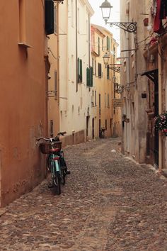 a bike parked on the side of a cobblestone street in an old town