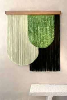 two green and black pieces of art hanging on the wall next to a white bench