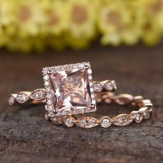 an engagement ring with a pink diamond surrounded by white diamonds on top of a piece of wood