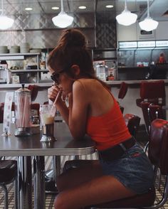 a woman sitting at a table with a blender in front of her and looking down