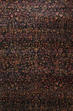 an old rug with many different colors and designs on the carpet, it is very dark