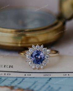 a blue diamond ring sitting on top of a piece of paper next to a magnifying glass