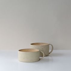 two white cups sitting next to each other on a table