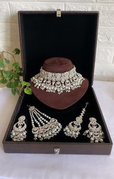 a brown hat and jewelry set in a black box on a white cloth tablecloth