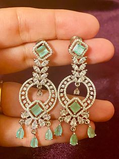 Our Mint CZ Silver finish AD Earrings, the perfect accessory for any Indian outfit or party gown. These earrings have a stunning silver finish, sure to elevate any ensemble. Add a touch of elegance and glamour to your wardrobe with these earrings today. Length - 6 cm Jewellery Care- Keep the jewelry dry, avoid heat and contact with perfumes & water. Jewellery With Gown, Glamorous Pierced Earrings For Formal Events, Elegant Pierced Danglers For Formal Occasions, Elegant Hand-set Danglers For Party, Glamorous Formal Bridal Earrings, Evening Cubic Zirconia Bridal Earrings, Glamorous Single Earring For Formal Occasions, Dazzling Silver Hoop Earrings For Party, Silver Pierced Chandelier Earrings For Festive Occasion