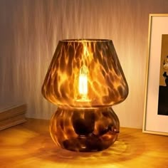 a lamp sitting on top of a wooden table next to a framed photo and an art print