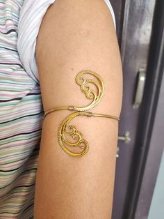 a woman's arm with a gold bracelet that has an intricate design on it