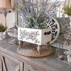 a table topped with lots of vases filled with purple flowers and greenery sitting on top of a wooden dresser