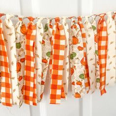 an orange and white checkered ribbon is hanging from a door with pumpkins on it