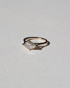 a gold ring with a single diamond in it on a white surface, close up