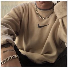 a man with a tattoo on his arm wearing a nike sweatshirt and chain link bracelet