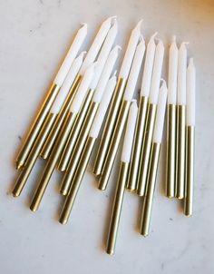 six gold and white candles lined up on a table