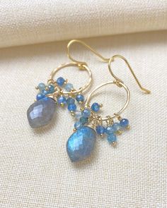 These earrings are a chic combination of rustic and refined. Sparkling, flashy labradorite briolettes are topped with clusters of petite blue kyanite gems and sway from gold-filled circles. The circles have been lightly hammered to a shimmering texture which reflects the light with every move. These gorgeous earrings will add a hint of sparkle and sophistication to any look. 14k gold-filled French wires. Earring drop: 1.5 inches Materials: gold fill, labradorite, kyanite Gift box included. Labradorite Earrings, Boho Luxe, Hammered Gold, Blue Kyanite, Earrings In Gold, French Wire, Cluster Earrings, Gorgeous Earrings, Labradorite