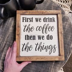 a hand holding a sign that says first we drink the coffee then we do the things