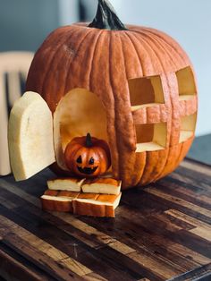 a carved pumpkin sitting on top of a wooden table next to slices of sliced bread