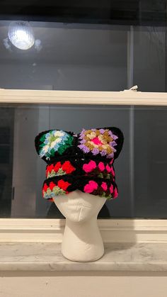 a white mannequin head wearing a multicolored knitted hat