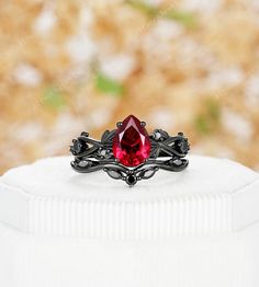 This black gold ruby ring is a stunning and enchanting piece that captures attention with its fusion of dark elegance and fiery passion. Crafted from Silver/10k/14k/18k white gold, plated with black rhodium, the ring creates a dramatic backdrop for the ruby centerpiece. The deep red ruby gemstone radiates with intensity and symbolizes love and strength. As the light catches the ruby, it illuminates the black gold band, creating a mesmerizing contrast. With its unique color combination and exquis Black Ruby Rings For Gifts, Black Ruby Rings As Gift, Black Ruby Rings For Gift, Black Round Ruby Ring, Round Black Ruby Ring, Black Ruby Ring Jewelry, Black Ruby Wedding Jewelry, Black Ruby Jewelry For Wedding, Wedding Black Ruby Jewelry