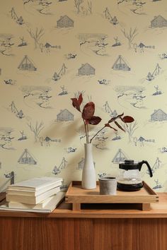 a wooden table topped with a vase filled with flowers next to a wallpapered wall