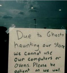 a sign posted in front of a store window that says due to ghost hunting our store we cannot use our computers or ovens please be patient as we wait