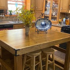 a kitchen island with two stools and a bowl on it in front of an oven