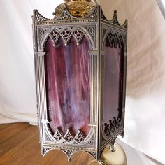 an ornate silver and purple lamp on a wooden floor