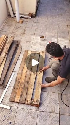 a man laying on the ground next to some wooden planks and making a hole