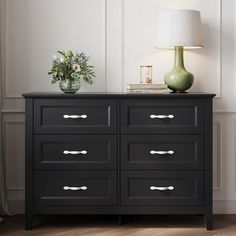 a black dresser with two vases and a green lamp on it's side