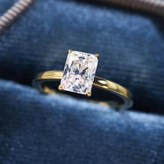 an engagement ring with a princess cut diamond in it's gold setting on a blue velvet bag