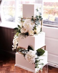 a three tiered cake with white flowers and greenery