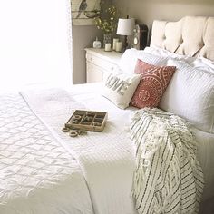 a white bed topped with lots of pillows