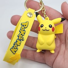 a hand holding a yellow pokemon key chain