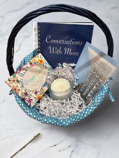 a basket filled with books, candles and other items on top of a white table