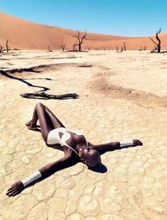 a woman laying on the ground in a desert