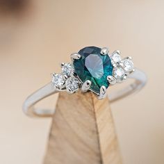 a close up of a ring with a green stone and white diamonds on it's side