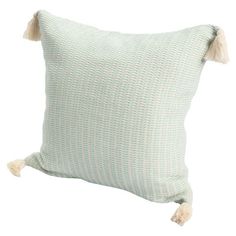 a green and white pillow with tassels on the sides, sitting against a white background