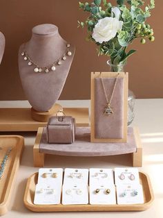 a table topped with jewelry and vases filled with flowers on top of wooden trays