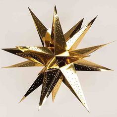 a gold and black star ornament hanging from the ceiling in front of a white background