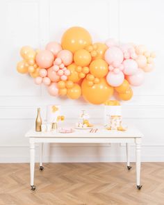 a table topped with lots of balloons on top of a wooden floor next to a wall