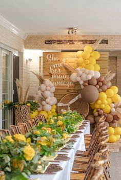 a table topped with lots of yellow and white balloons