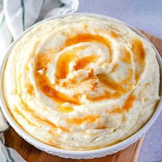 a white bowl filled with mashed potatoes on top of a wooden cutting board