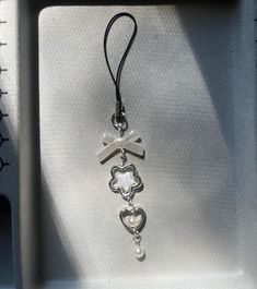 a silver cross and heart charm hanging from a black cord on a white cloth covered box