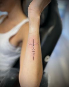 a woman's arm with a tattoo that reads faith on the cross in cursive writing