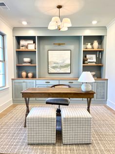 an office with two chairs and a desk in the center, along with built - in shelving