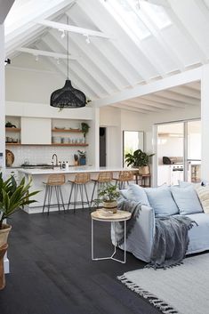 a living room filled with furniture next to a kitchen and dining room table on top of a hard wood floor